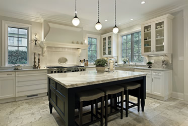 Bright white kitchen with granite counter tops with three pendant lights above island countertop